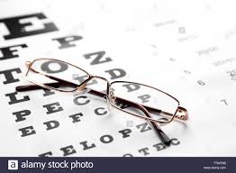 glasses lying on eye test chart close up view healthy eyes