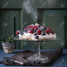 Using a large spoon make a shallow trench in the meringue for the cream and fruit to sit in. Vintage Cake Stand With Meringue Dessert Pavlova With Fresh Blackberries And Raspberries Strewing By Sugar Powder Over Blue Wooden Table Dark Rustic Style Square Image Stock Photo Picture And Royalty Free Image