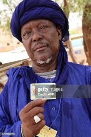 Ousmane Alamine Toure holds up his NINA card, a recently introduced... News  Photo