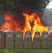 A row of port o potties on fire.