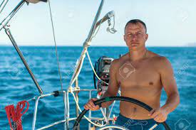 Young Man With Naked Body At The Helm Of A Sailing Yacht Boat. Stock Photo,  Picture and Royalty Free Image. Image 80748202.