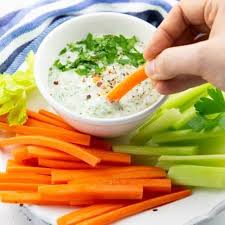 A Hand Dipping A Carrot Stick In A Small Bowl Of Vegan Ranch On A Plate With Carrot And Celery Sticks Delicious Healthy Recipes Vegan Snacks Vegan Ranch