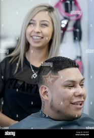 Diana Martinez, owner of Studio Cutz Beauty & Barber, and client Albert  Sanchez share a laugh as they talk after she designed a star representing  the Houston Astros logo into his fade