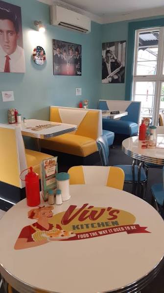 Retro booths and a table printed with the Viv's Kitchen logo and slogan, Food the way it used to be