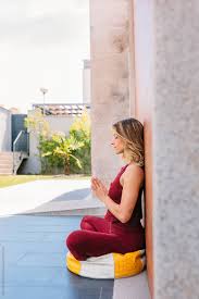 Join us for an explorative practice where you'll attune to your soothed self. Beautiful Young Woman Doing Namaste Yoga Posture While Leaning On Concrete Wall By Victor Torres