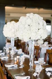 A luxurious wedding centerpiece of pink, red and burgundy blooms. Tall Centerpieces Of White Hydrangea And Roses By Lark Floral For S White Floral Centerpieces White Wedding Flowers Centerpieces Carnation Wedding Centerpieces