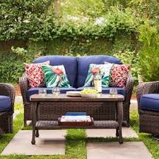 A Patio Conversation Set With A Wicker Coffee Table Wicker Patio Chairs Outdoor Cushions Patio Furniture Wicker Patio Furniture Sets