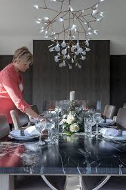 The chairs are all made from wood and they come with a comfortable high back design, uniquely curved legs, and an incredible combination of white and black color palette for perfect contrast. Interior Designer Setting Out A Dining Table And Arranging The Settings Black Granite Table With Floral Centre Piece By Paul Phillips Stocksy United