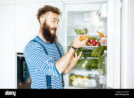 Man Taking Fresh Carrot From The Fridge Full Of Fresh Vegetables And Fruits At Home Stock Photo Alamy