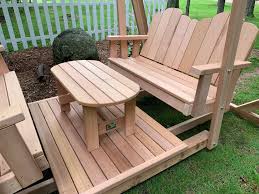 It consists of a rectangular table, 2 benches for 2 persons each and a brown canopy. Framed Four Seat Cedar Swing W Center Platform Table
