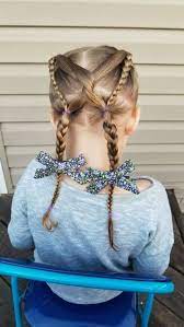 Two Crossed Braids Two Floral Bows Cute Simple Hairstyles Blonde Hair Blue Chair Grey Blouse Hair Styles Girls Hairstyles Easy Cute Hairstyles