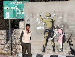 Banksy is a contemporary british street artist and activist who, despite his international fame, has maintained an anonymous identity.aimed as a form of cultural criticism, the artist often targets established social and political agendas with his witty illustrations produced with stencils and spray paint in cities such as new orleans, new york, and paris. Banksy In Palestine A Look At The Street Artist S Work In Gaza And The West Bank