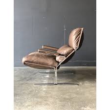 Large brown leather chair and cushioned ottoman made with 100% cow leather, teak wood, and individual nail heads. Westnofa Siesta Leather Chair Ottoman Chairish