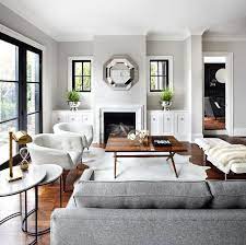 A grey and white bedroom, a small side table with a coral cover, grey, white and coral bedding with a print and a copper lamp. Transitional Living Room The Design Company Living Room Grey Living Room Designs Grey Interior Design