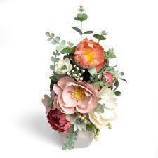 Set within a clear glass vase filled with shells, in acrylic water, is a bouquet of white pom poms, eucalyptus and feather ferns. Eucalyptus Floral Arrangement