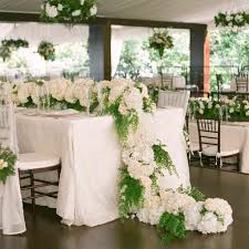 The bare wooden table is covered in a trail of oversized tropical leaves dotted with white poppies and green orchids. 29 Fresh Floral Table Runners For Every Wedding Style