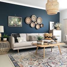 A Dark Blue Accent Wall With Cream Sofa Wicker Baskets Used As Art And A Rug Tha Interior Design Living Room Warm Interior Design Living Room Blue Living Room