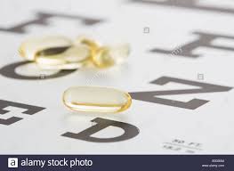 vitamins gel capsules lying on eye chart stock photo