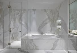 A small yet luxurious marble powder room with chevron clad walls and a chic mirror plus wall lamps. White Marble Bathrooms Atticmag