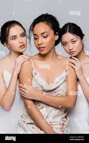 Pretty brunette interracial women touching african american friend isolated  on grey Stock Photo - Alamy