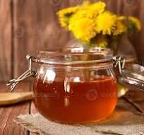 Natural honey in a transparent jar with flowers as ...