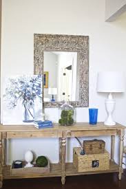 Smoked mirror top and table displaying a blue antique lamp along with florals for a classic and elegant design aesthetic. Entry Table Decor 2 Bees In A Pod