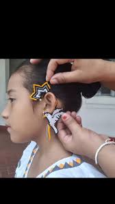 Elin, vestida con orgullo en su vestido blanco tradicional, recibe con  ternura los aretes Eart Curff hechos en chaquira, un símbolo de paz y  nuestras raíces Ngäbe-Buglé., Este momento es más que un ...