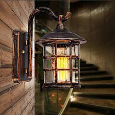 This outdoor wall light fixture features a ribbed frost lens with a metal wire guard over it, shielding its single light bulb and lens. Antique Rustic Iron Waterproof Outdoor Wall Lamp Vintage Lantern Light Rusty Matte Black Corridor Hallway Wall Sconce Lighting Pop