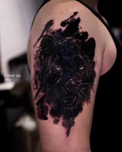 Realistic black panther shoulder cover-up tattoo with deep black shading and high-contrast detail designed to fully transform an older tattoo underneath. Strong composition, layered textures, and smooth black and grey realism create