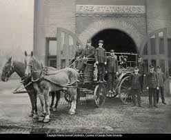 Firemen on horse-drawn fire-truck ...
