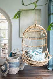 gray and blue woven baskets sit beside a serena lily hanging rattan chair hung in front of a green abstract hanging chair indoor chairs hanging rattan chair