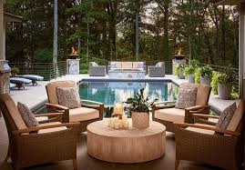 Wicker Chairs Topped With Cream Cushions And Black And White Pillows Sit In Front Of An In Ground Pool And Surround Outdoor Living Patio Outdoor Deck Furniture