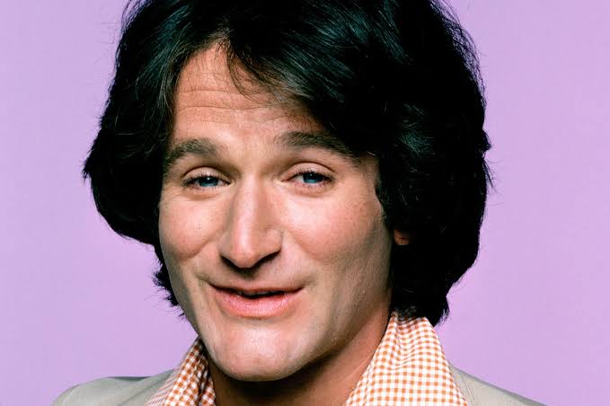 Poltronas de cinema iluminadas pela tela, simbolizando o legado cinematográfico de Robin Williams