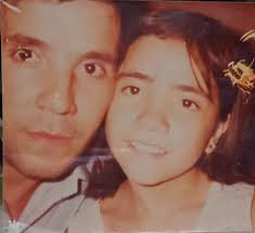 Quisiera poder restaurar esta foto..Eso que tiene en las manos es un  ramo..No importa no salga completo solo Quisiera recuperar la foto y dale  color..El vestido es de los óvalos negro y