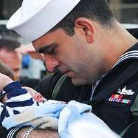 A Sailor greets his wife and newborn baby moments after arriving aboard the  aircraft carrier USS Abraham Lincoln (CVN 72).