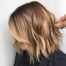 Hand Holding A Strand Of Wavy Light Brunette Hair With Natural Looking Blonde Streaks Brown Hair With Blonde Highlights Brown Blonde Hair Blonde Highlights