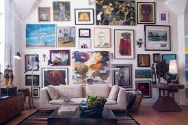 Eclectic living room with sleek coffee table and a yellow couch that adds a striking contrast to the purple accent wall mounted with a stag head decor. Tips And Ideas For Creating A Beautiful Wall Art Gallery Gallery Wall Living Room Eclectic Living Room Art Gallery Wall