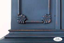 Crafted from manufactured wood in a navy blue hue, this piece features a traditional cabinet front with three drawers and three doors adorned by a decorative wood design on their glass fronts. Milk Painted Vintage China Cabinet Eight Hundred Furniture