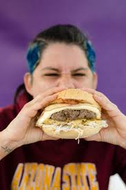 Person holding burger with patty and cheese photo