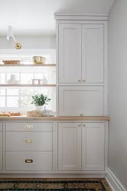 wood floating shelves are stacked in front of a window lit by a white and gold sconce and mounted over and be in 2021 kate marker interiors interior kitchen redesign