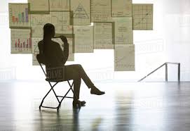 Businesswoman Studying Charts And Graphs On Wall In Office D985_12_549