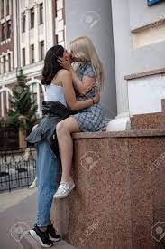 Blonde Lesbian Sitting On Wall And Kissing Her Brunette Girlfriend.  Spending Time In The City. Stock Photo, Picture and Royalty Free Image.  Image 110423922.