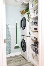 Laundry area with white cabinets, washer and dryer, clothes hanging on rack on built in shelf, storage compartments, and wicker laundry basket on floor. 27 Clever Laundry Room Ideas How To Organize A Laundry Room