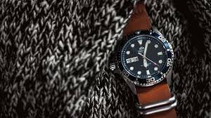 Experienced craftsmen following a tradition of excellence. Wristwatch Round Black Analog Watch With Brown Leather Strap On Black And White Knitted Textile Texture Image Free Stock Photo