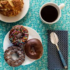 Desayuno De Donas Donas De Chocolate Sobre Plato Blanco Acompanadas De Cafe Y Pan Mantel Color Verde Celeste Con Una Servilleta Azul Mar Food Desserts Donuts