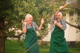 Playful Senior Couple In Outdoor Garden Outside Garden Hose Water Sprinkle Summer Spring Danberry At Inverness Birmingham Alabama