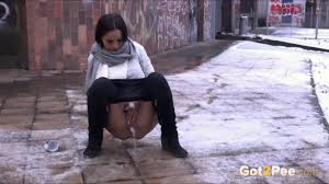 Frau pisst im Winter in einer Stadt