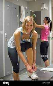 Smiling fit woman tying shoelaces at gym's locker room Stock Photo - Alamy