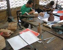 A Cambodian artisan carefully carving an intricate design into wood.