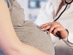 Doctor examining a pregnant patient's abdomen with a stethoscope